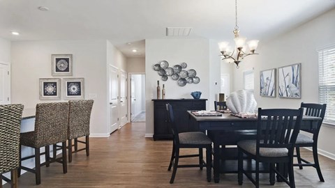 A dining room with a table set for two and a chandelier hanging from the ceiling.