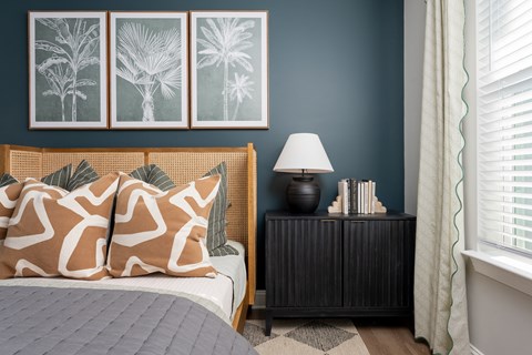 A bedroom with a bed, a nightstand with a lamp, and three framed pictures on the wall.
