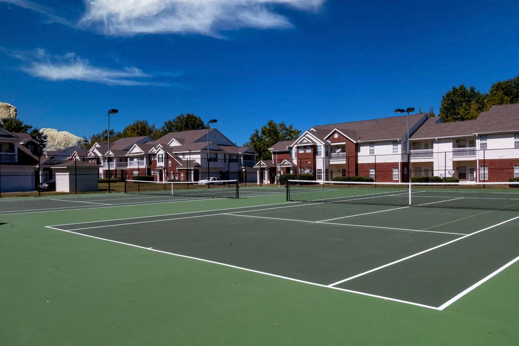 a tennis court with apartments in the background