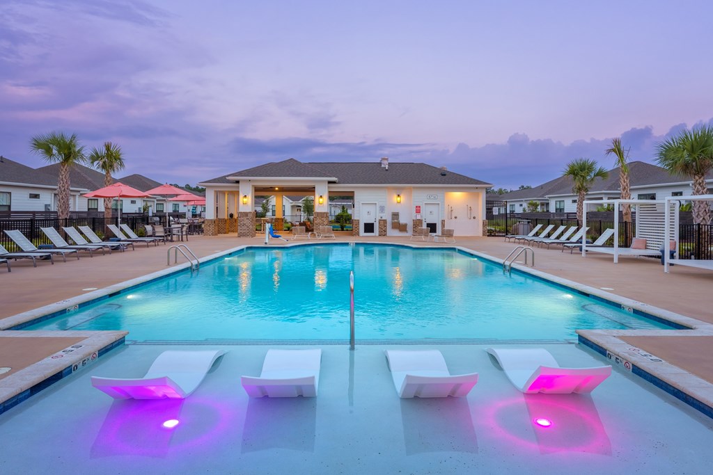 A pool with purple lights and a house in the background.