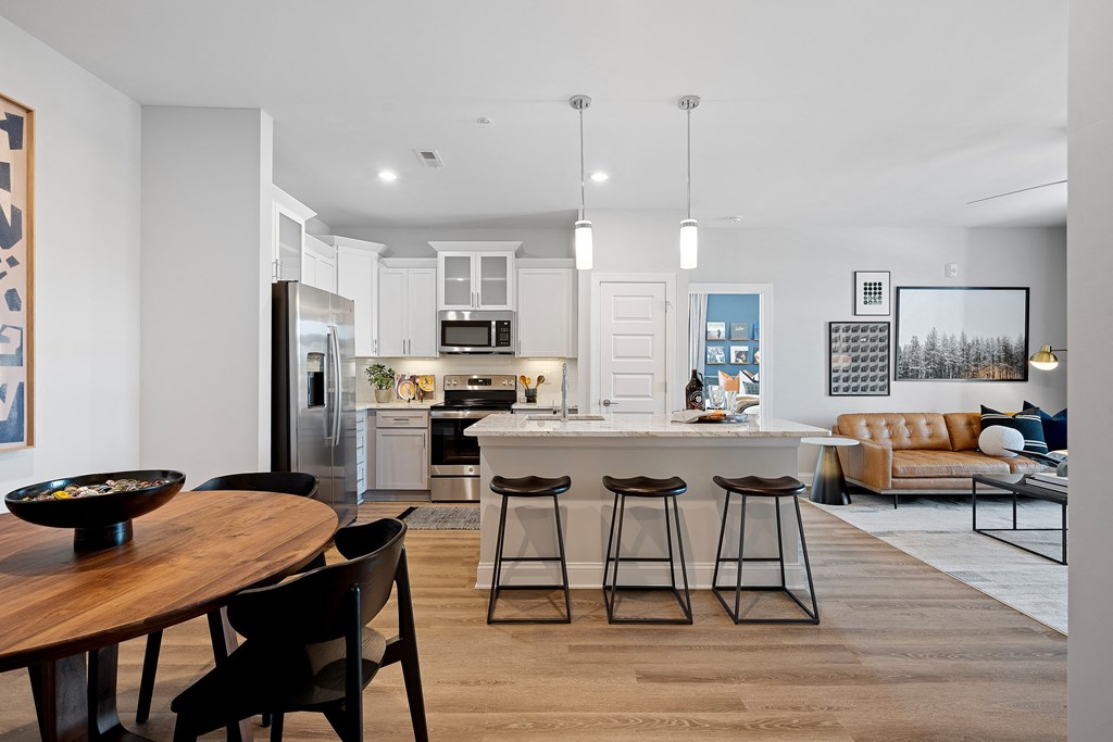 a kitchen and living room with white walls and wood flooring