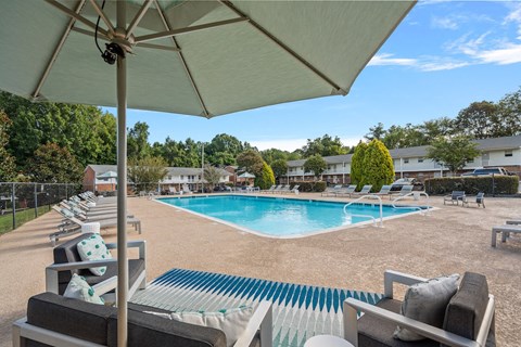 a swimming pool with chairs and an umbrella at a resort