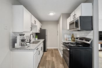 an empty kitchen with white cabinets and black appliances