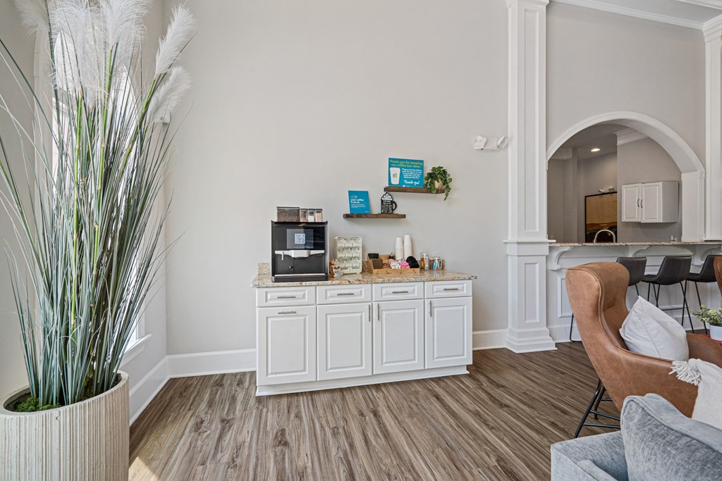 a room with a coffee bar and a kitchen in the background