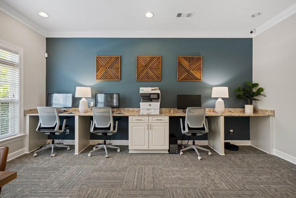 a large desk with four computers and three lamps in an office with a blue accent wall