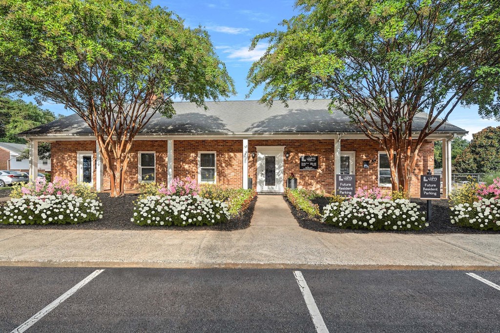 the front of a brick building with trees and flowers