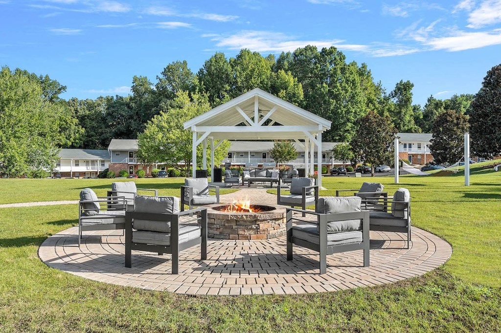 a patio with chairs and a fire pit in a park
