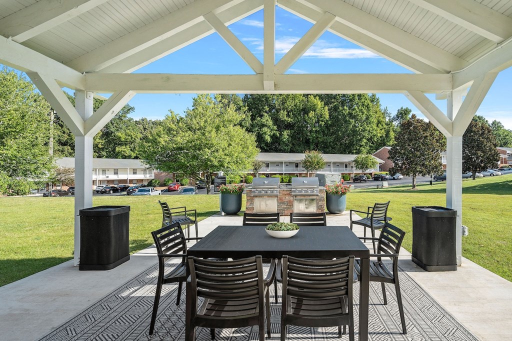 a dining area with a table and chairs under a pavilion