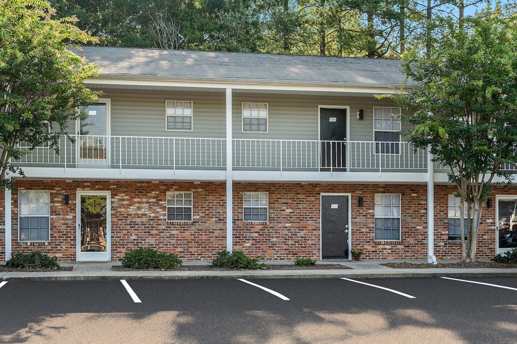 a red brick building with a balcony and a parking lot