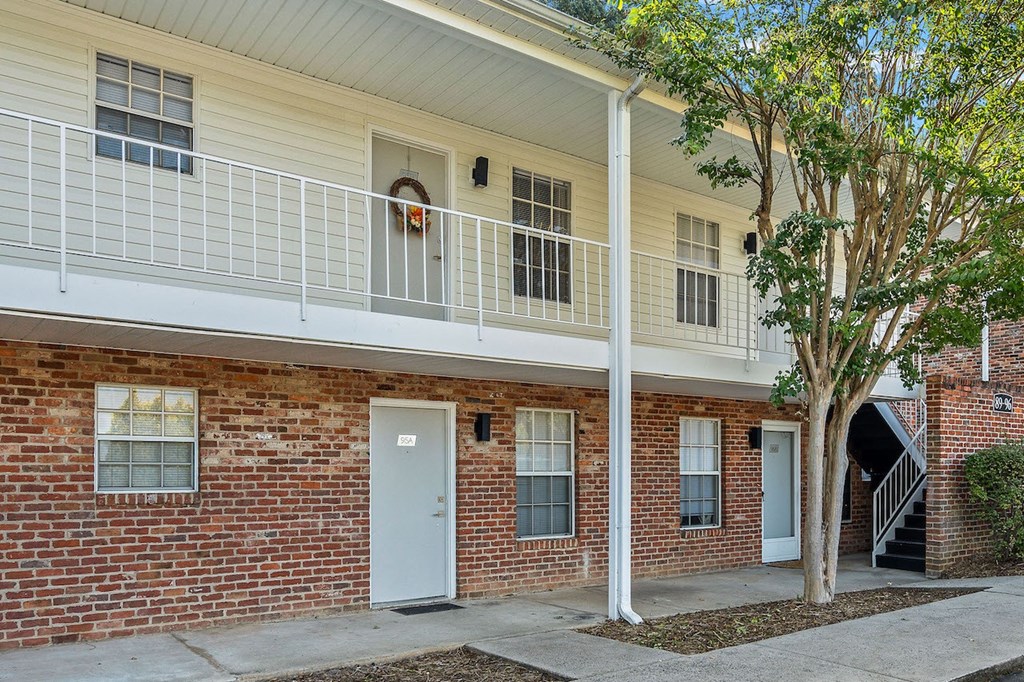 the front of a brick building with a white balcony and a white door