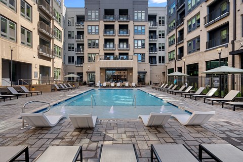 A large swimming pool surrounded by lounge chairs in a courtyard.
