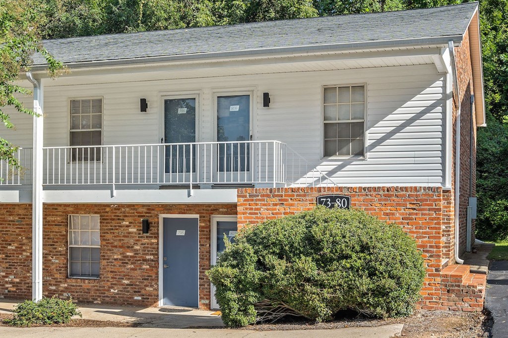 the front of a brick building with a porch and a sign on the side