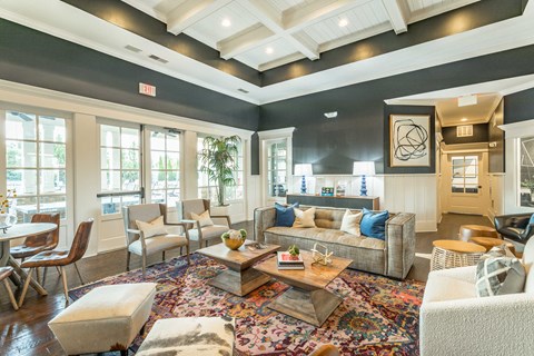 A living room with a large rug and a variety of seating options.