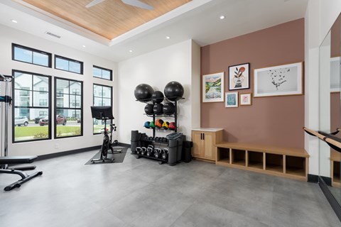 A gym room with a bench, weights, and exercise equipment at Evolve Holly Ridge Apartments in Holly Ridge, NC.