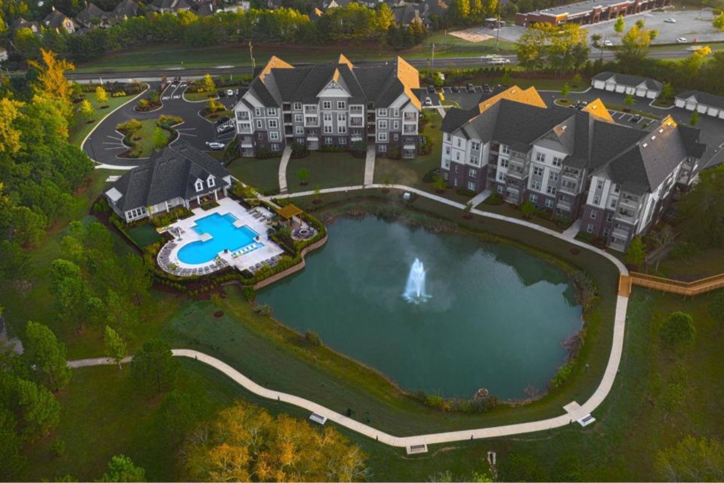 A large resort with a fountain in the middle of a pond.