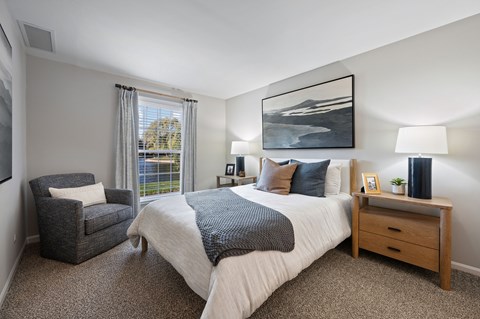 Bedroom with modern furnishings and natural light at Versailles on the Lakes Schaumburg Apartments, Schaumburg, Illinois