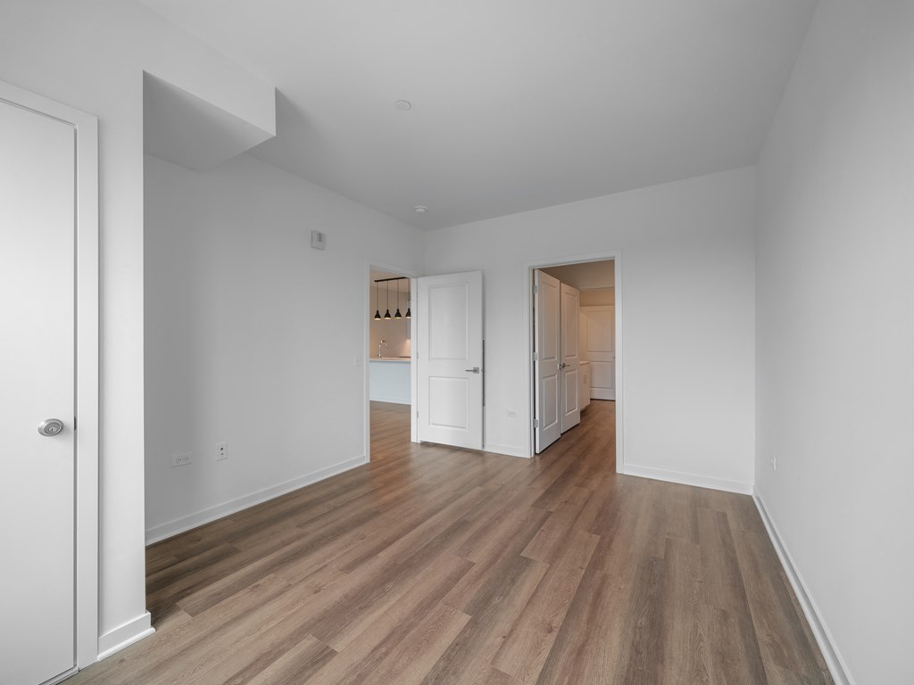 a living room and kitchen with white walls and wood floors
