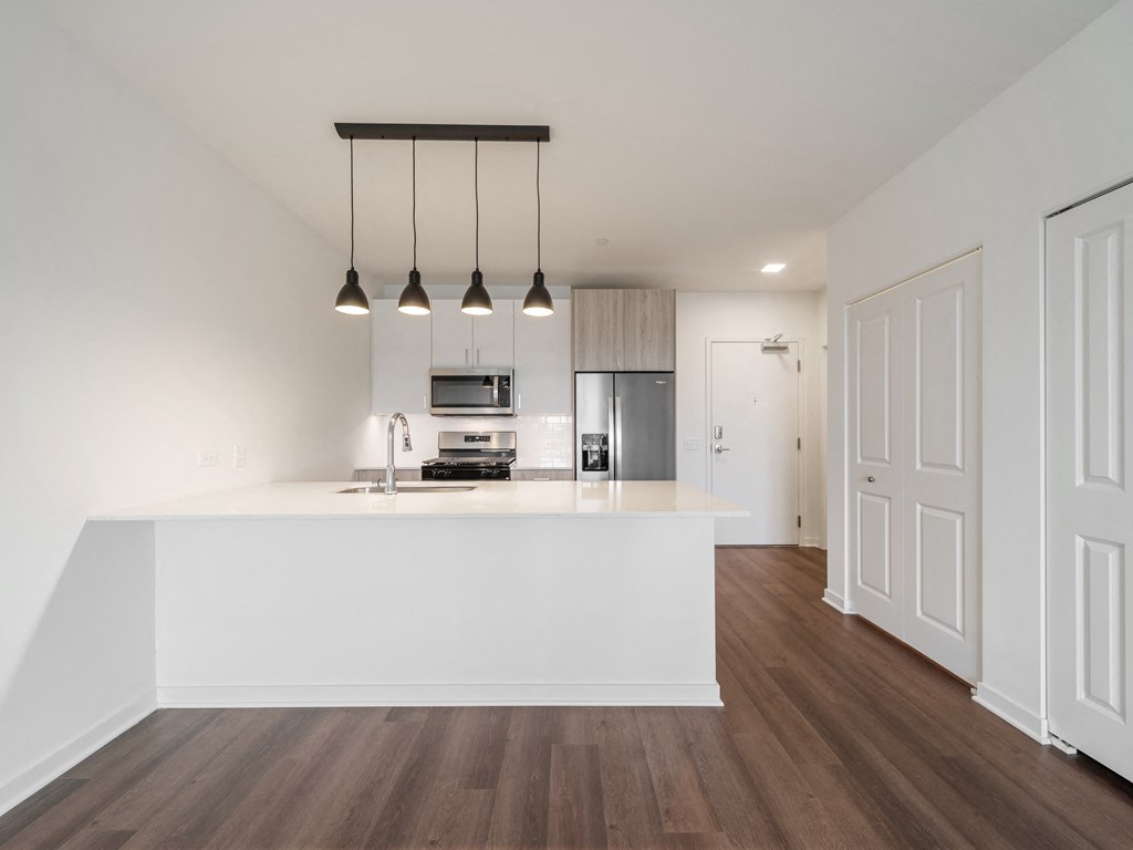 an open kitchen and living room with a white counter top and a white kitchen island