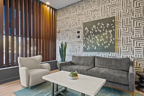 A living room with a grey couch, a white coffee table, and a painting on the wall.