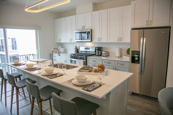 a kitchen with a large island and a stainless steel refrigerator at Enclave Crystal Lake Townhomes and Apartments, Crystal Lake, Illinois