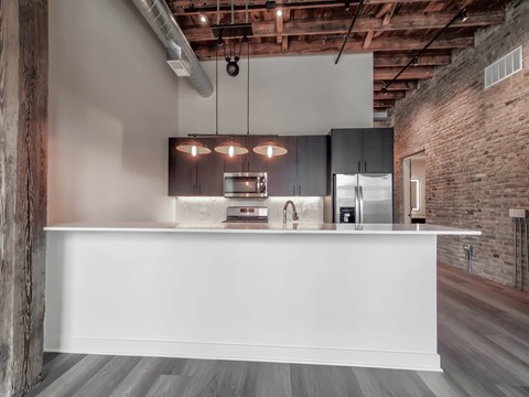 A modern kitchen with a white countertop and wooden beams on the ceiling.