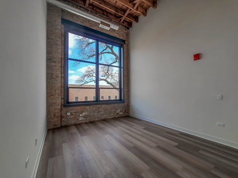 A room with a large window and wooden flooring.