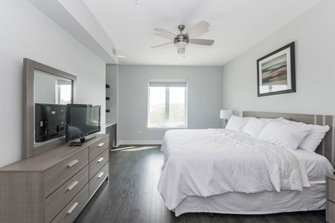 A bedroom with a large bed, a television, and a ceiling fan.