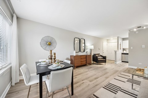 A dining room with a table set for two and a white chair.