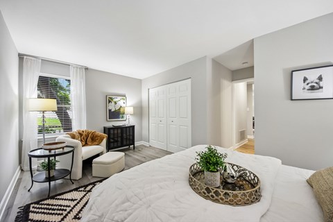 A bedroom with a large bed and a small table with a plant on it.