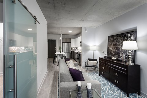 A modern living room with a grey couch and a black dresser.
