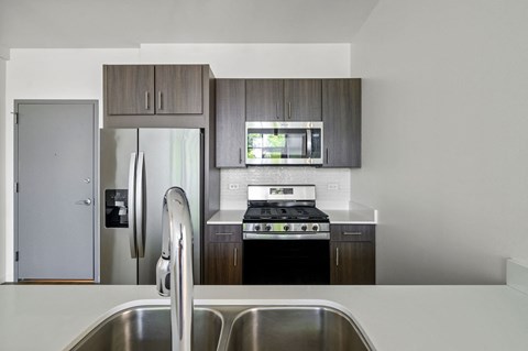 A modern kitchen with a stainless steel sink and a refrigerator with a water dispenser.