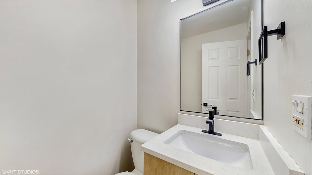 A white sink in a bathroom with a mirror above it.
