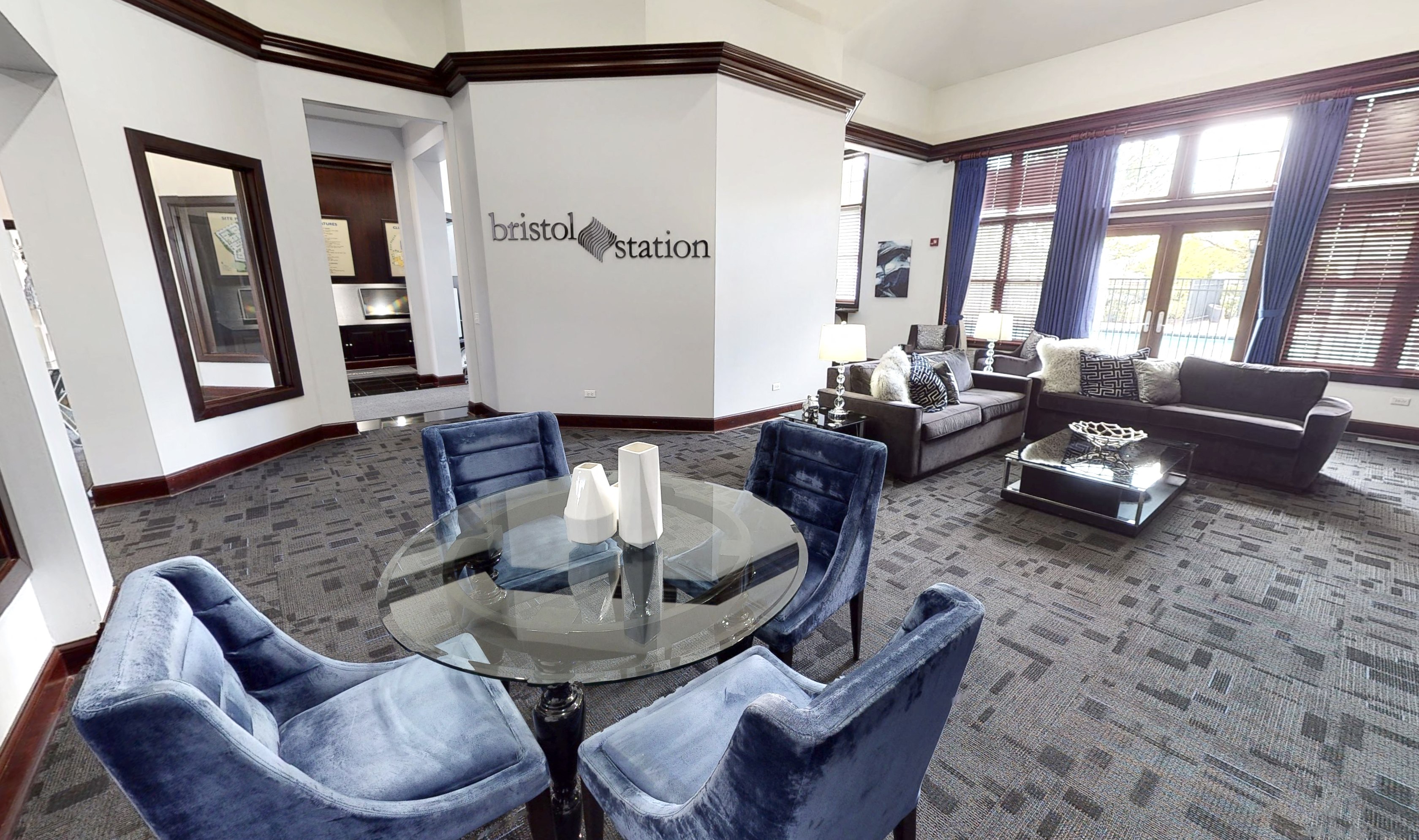 A living room with a glass table and blue chairs.