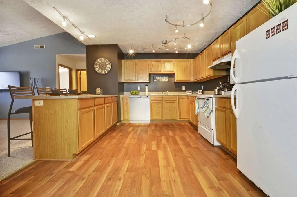 a large kitchen with wooden floors and white appliances