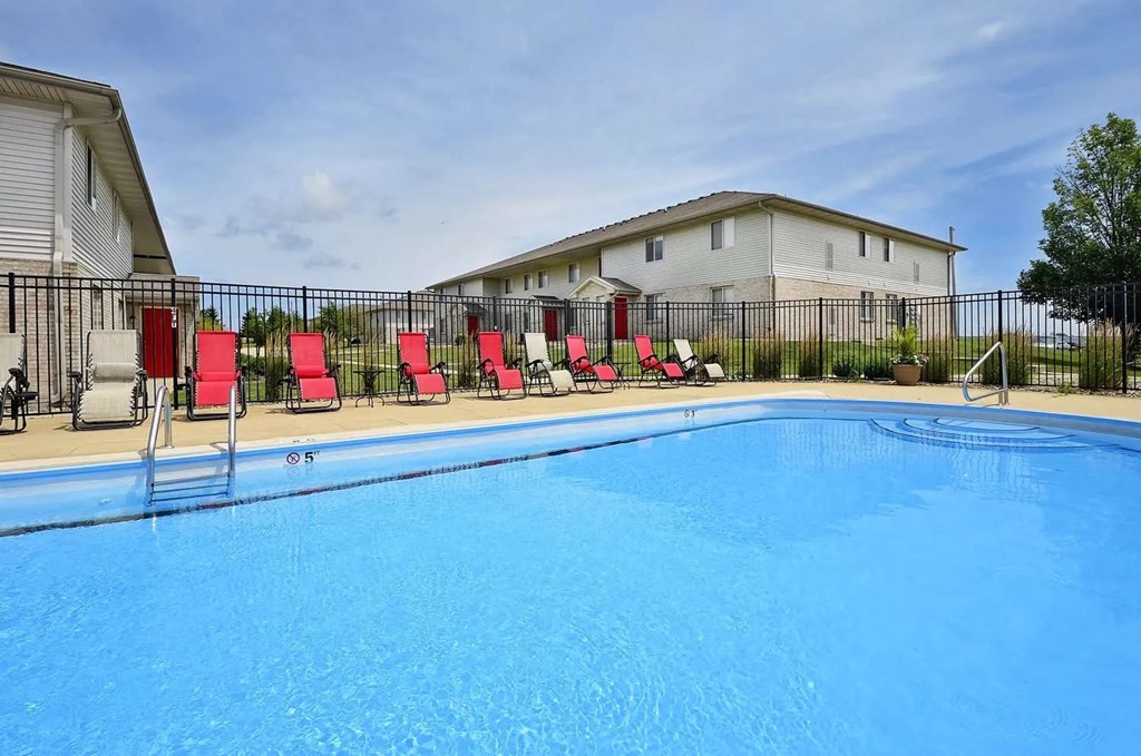 a swimming pool with chairs and a house in the background