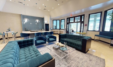 A living room with a large green couch and a glass coffee table.