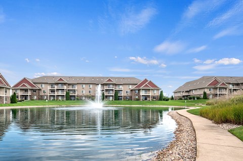 A serene lake in front of a row of apartment buildings.