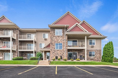 A large apartment building with a parking lot in front.