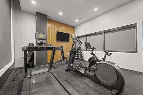 A treadmill and a stationary bike are in a room with a wooden panel wall.