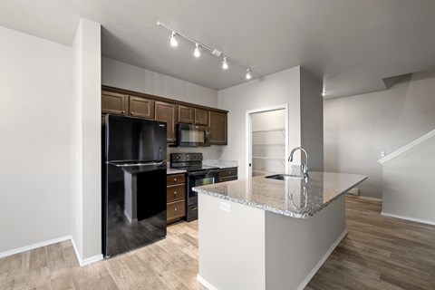 A kitchen with a black fridge and stove top oven.
