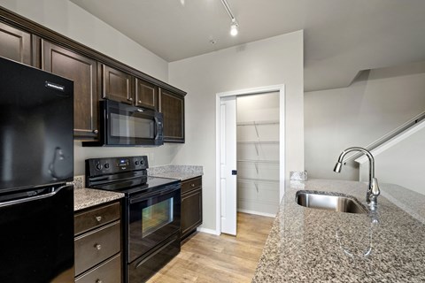 A kitchen with black appliances and wooden cabinets.