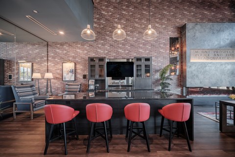 a bar with red chairs in front of a kitchen with a tv