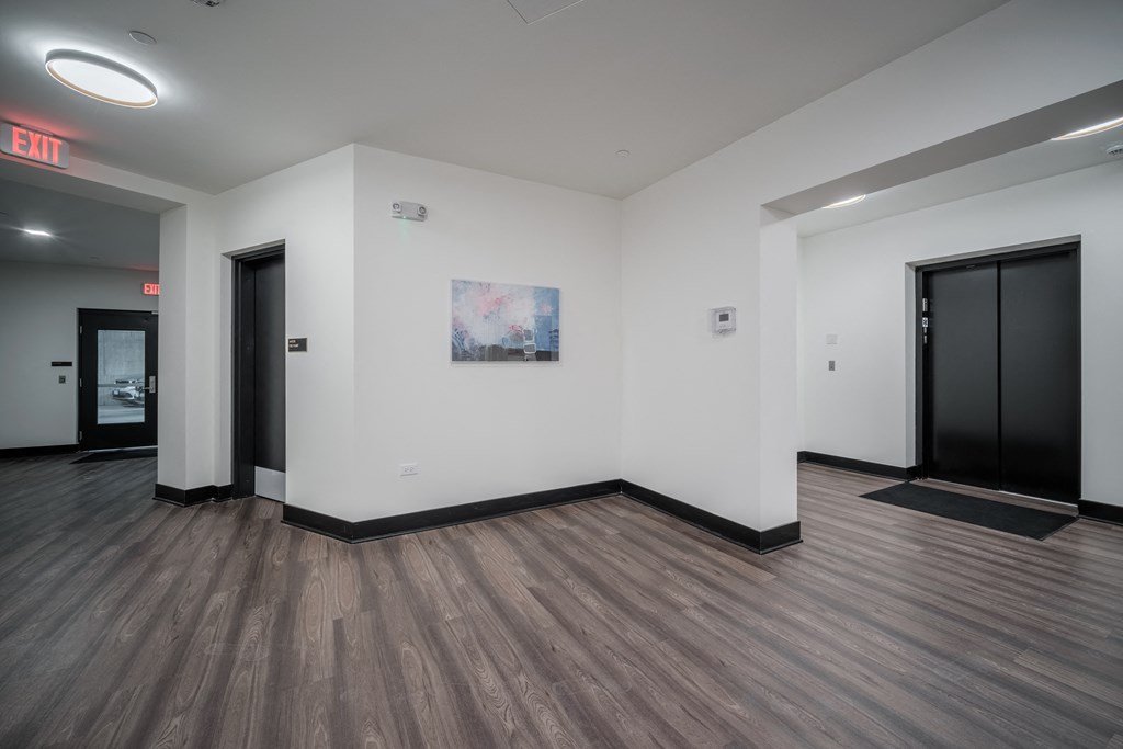 a large room with white walls and wooden floors and two black doors
