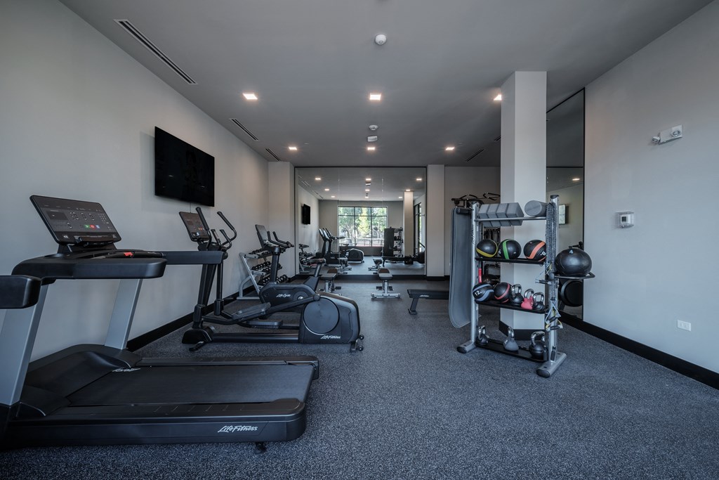 a gym with treadmills and other exercise equipment and a tv