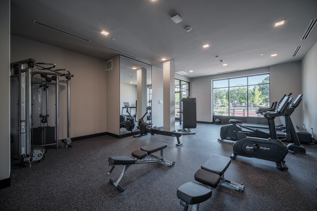 a gym with weights and exercise equipment and a window