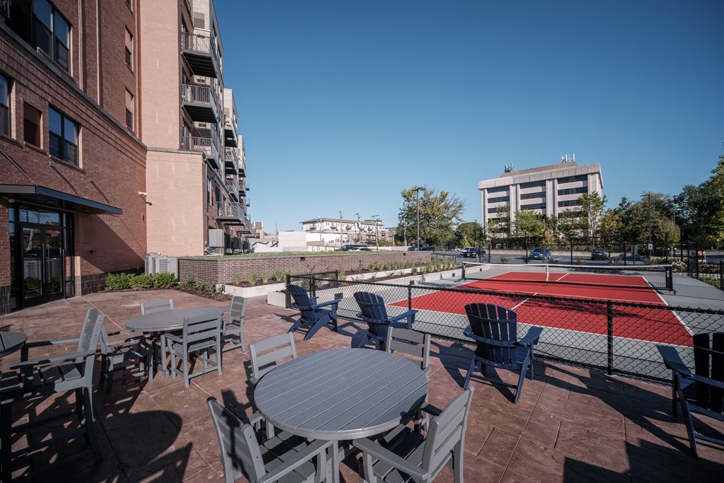 a patio with a table and chairs and a tennis court