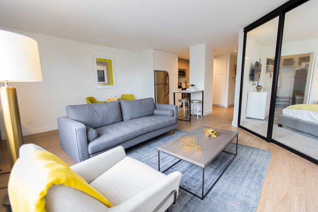 a living room with a couch and a coffee table and a bedroom with a bed at The Kent, Chicago