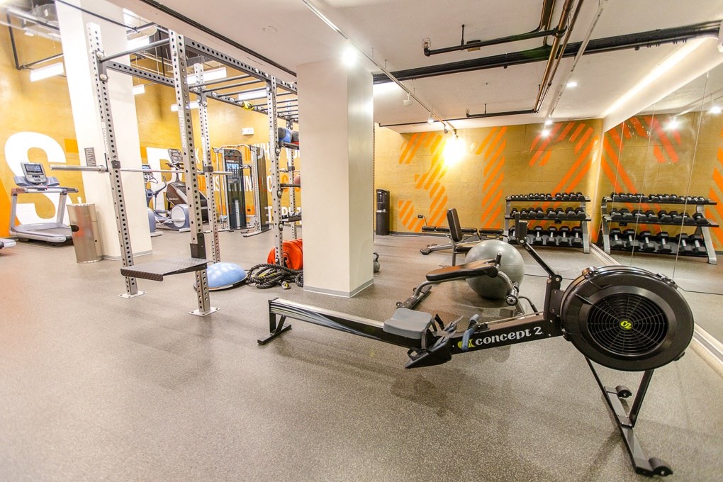 a gym with weights and other exercise equipment in a building with orange walls at The Kent, Chicago, IL