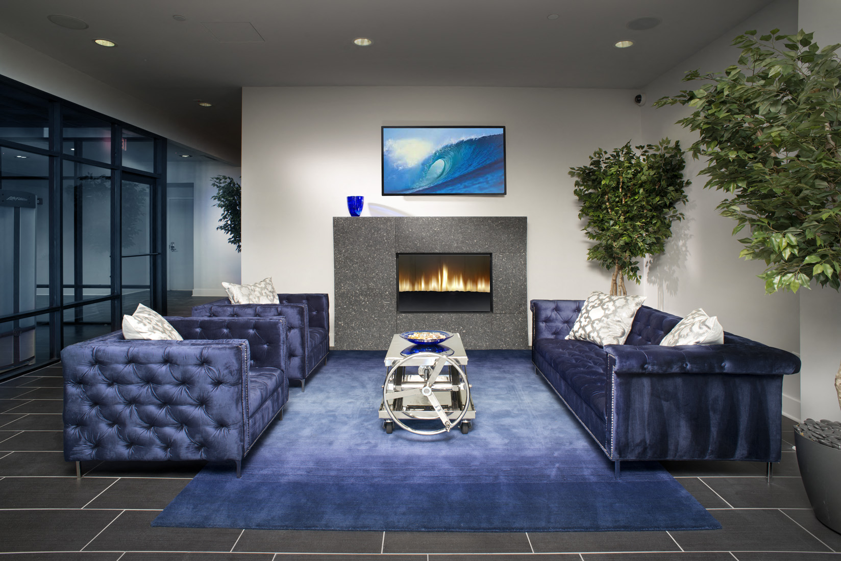 A living room with a blue couch and a television on the wall.