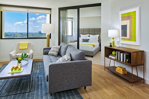 A modern living room with a grey couch and a large window.